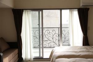 a bedroom with a bed and a large window at Condominium Hotel Monpa in Chatan
