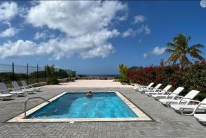 a swimming pool with chairs and the ocean in the background at Punta Azul in Westpunt