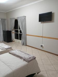 a bedroom with two beds and a flat screen tv at 9 wena Ave Guesthouse in Klerksdorp