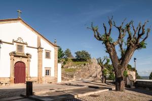 a church with a tree in front of it at Casa do Adro in Idanha-a-Nova