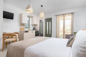 a white bedroom with a large bed and a kitchen at Kefalas Luxury Villas Kelari Accessible Stone Studio in Epáno Kefalás