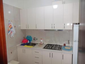 uma cozinha com armários brancos, um lavatório e um frigorífico em Buoy Rooms em Batumi