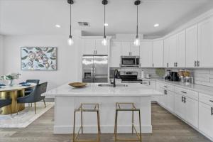 una cocina con armarios blancos y una gran isla con taburetes. en High Style in H-Town with Luxury near Downtown, en Houston