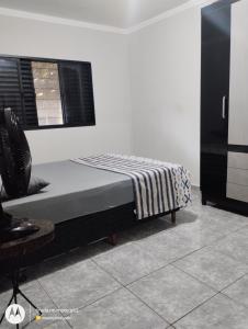 a bedroom with a bed and a chair and a window at Seu lugar de paz in Sarandi