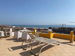 a patio with chairs and tables on a roof at A7 Maison Blanche Imi ouaddar in Agadir