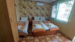a small room with two beds and a window at Вила Радеви in Obzor