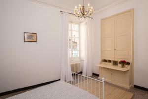 Habitación blanca con lámpara de araña y escalera en Casa Carducci - Spacious historical home close to the beach, en Imperia