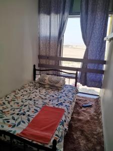 Cama en habitación con ventana y manta roja en The Serene Spot, en Abu Dabi