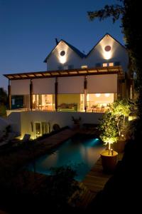 een groot huis met een zwembad in de nacht bij Four Rosmead Boutique Guesthouse in Kaapstad