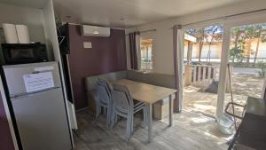 a small kitchen with a table and chairs and a refrigerator at Mobil home haut de gamme 6 personnes camping 4 étoiles Marvilla Parks BARCARES plage in Torreilles +8 photos