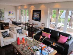Four Rosmead Boutique Guesthouse في كيب تاون: غرفة معيشة مع أريكة جلدية سوداء ووسائد وردية