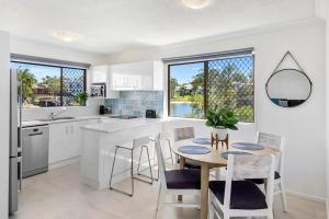 a kitchen with a table and chairs in a kitchen at Beautiful Modern Waterfront Apartment on the Canal in Mooloolaba +4 photos