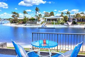 a table and chairs on a balcony with a body of water at Beautiful Modern Waterfront Apartment on the Canal in Mooloolaba