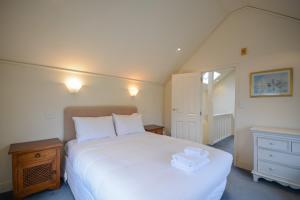 a bedroom with a large white bed and a dresser at Waterfront Akaroa Retreat with Harbour Views & Balcony in Akaroa