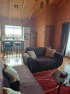 Una sala de estar con un sofá y una cocina. en Cabañas Kaykun, en Puerto Octay