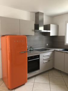 an orange refrigerator in a kitchen with white cabinets at Villa du Bonheur Carambole in Saint-Georges-dʼOléron