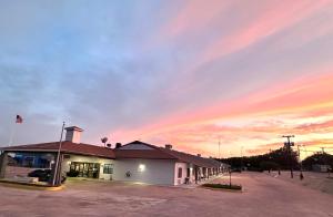 a building in a parking lot with a sunset at Sunset Inn in Brady