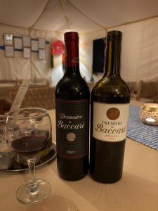 two bottles of wine sitting on a table with a glass at Mhamid Amazing Camp in Mhamid