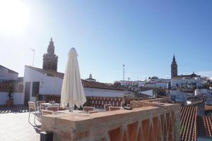 a patio with a white umbrella and chairs and buildings at La joya de la Alcazaba in Jerez de los Caballeros