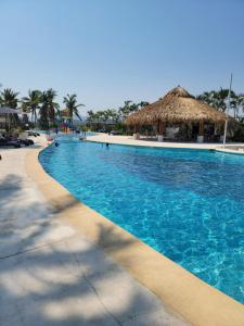 une grande piscine bleue avec un chaume dans l'établissement Terrasol Diamante, à Acapulco