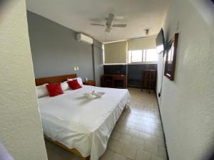 a bedroom with a large white bed with red pillows at Hotel Italia, Aguascalientes in Aguascalientes