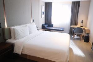 a hotel room with a large white bed and a desk at Atour Hotel Shanghai Xianxia in Shanghai