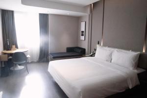 a hotel room with a white bed and a chair at Atour Hotel Shanghai Xianxia in Shanghai
