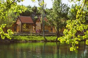 a log cabin next to a lake with trees at River huts Zrmanja in Obrovac