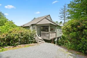 a green house with a porch and a driveway at Mountain View 3BDR with Hot Tub, Game Loft and Deck in Sugar Mountain
