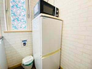 een witte koelkast met een magnetron erop bij Yume House in Furano +36 foto's