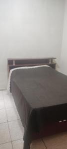a bed with a black blanket on top of it at Casa Lagoa Santo Antônio in Laguna