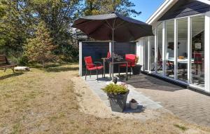 a patio with a table and chairs and an umbrella at Holiday Home Grårisvej Thisted V in Nørre Vorupør