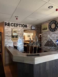 a bar in a restaurant with a clock on the wall at Motel Le Villageois Du Lac in Saint-Francois-du-Lac