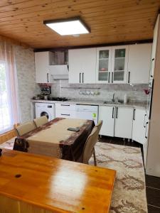 a kitchen with a wooden table and white cabinets at Çay Pansiyon in Uzungöl