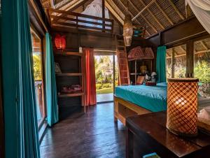 a bedroom with a bed and a table in a room at Cute Eco Cottage Near 7 Waterfalls in Singaraja