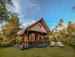 a house with a thatched roof and two chairs at Cute Eco Cottage Near 7 Waterfalls in Singaraja +170 photos