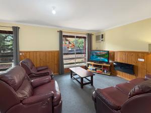 Una sala de estar con un sofá y un televisor. en Rosella Views, en Mount Buller