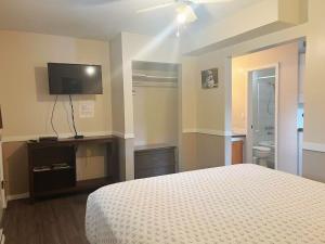 a bedroom with a bed and a flat screen tv at Rivermount Motel in Little Fort