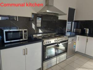 a kitchen with a stove and a microwave in it at Maruve Guesthouse 12 min from Melb airport in Melbourne