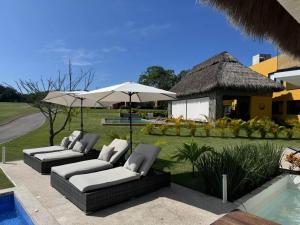 a patio with two couches and an umbrella next to a pool at Naisári Residencia Punta de Mita María Bonita in Higuera Blanca