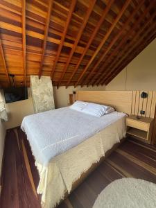 a bedroom with a large bed with a wooden ceiling at Chalé Positano-RecantoVenâncio in São Bento do Sapucaí