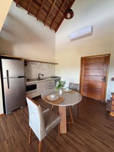 a kitchen with a table and a refrigerator at Chalé Positano-RecantoVenâncio in São Bento do Sapucaí +10 photos