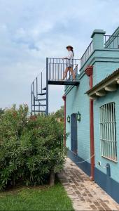 サン・アントニオ・デ・アレコにあるEl Sendero - Güiraldes B&Bの青い建物のバルコニーに立っている男性