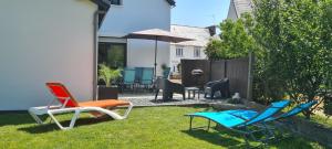 a yard with chairs and tables and an umbrella at Maison entièrement rénovée, jardin & terrasse à 5min des plages in Combrit
