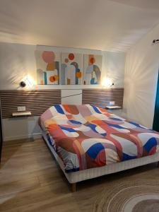 a bedroom with a bed with a colorful comforter at Maison entièrement rénovée, jardin & terrasse à 5min des plages in Combrit