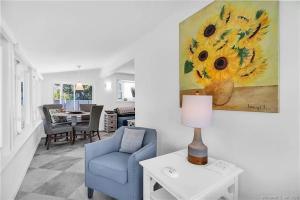 a living room with a blue chair and a painting at Charming Beach Cottage in Westbrook