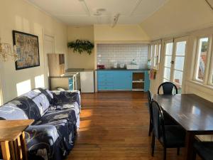 a living room with a couch and a table and a kitchen at Chalet Backpackers in Dunedin