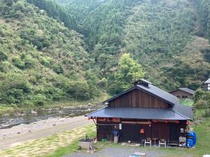 京都cafe & guesthouse 魚ヶ淵的山旁的河边的建筑物