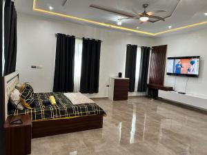a living room with a bed and a flat screen tv at Nanani Luxury Villa - 3 Bedrooms in Kumasi