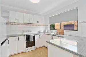 Una cocina con gabinetes blancos y una ventana grande. en The Station Mornington, en Mornington
